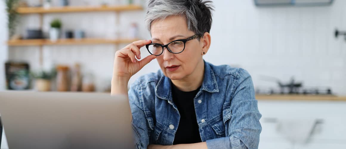 Older woman with a confused expression in front of her laptop.