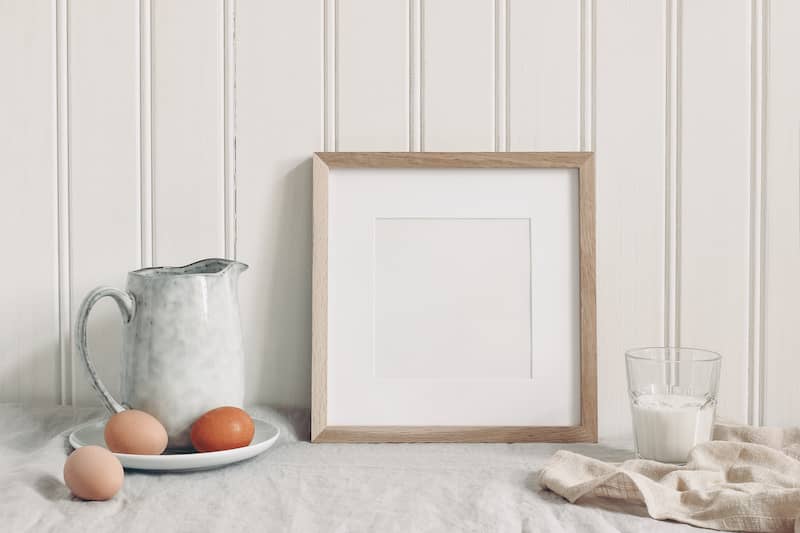 White bead board backsplash with white ceramic pitcher and fresh brown eggs on counter top.