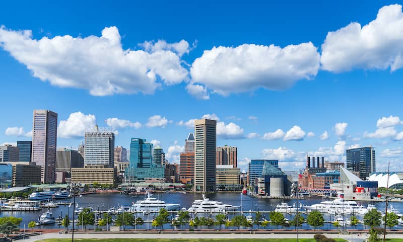 RHB Assets From IGX: Baltimore waterfront skyline at sunset with harbor reflections.