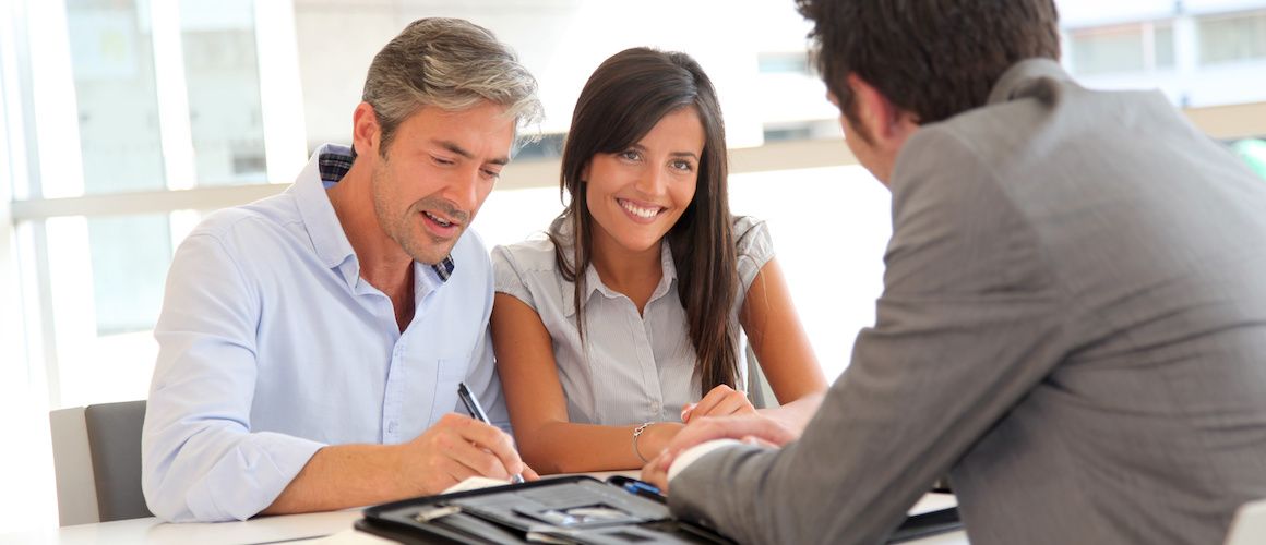 A couple discussing finances or mortgages with an agent.