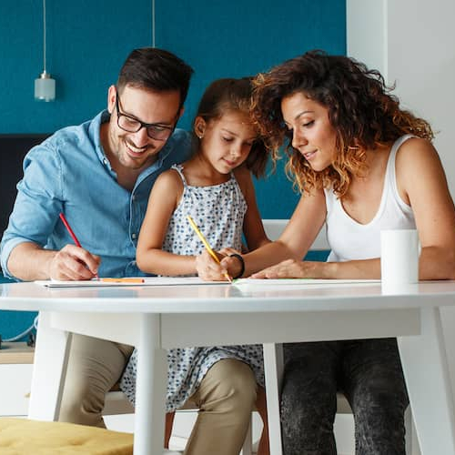Image of a mother and father drawing with their child, suggesting a family-oriented activity.