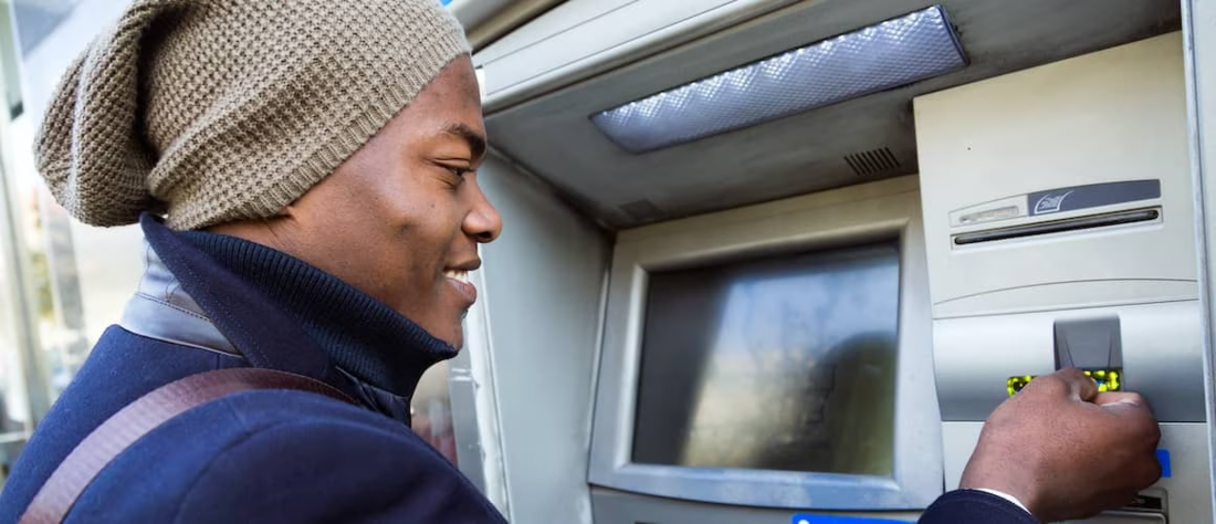 African American man in a beanie using an ATM.