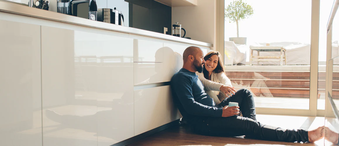 A couple seated together on the kitchen floor.