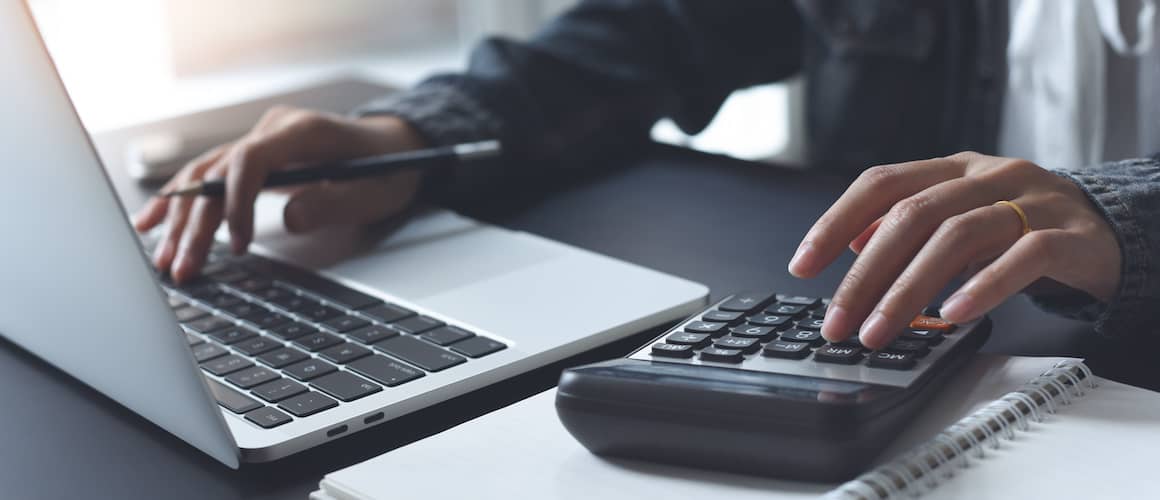 RHB Assets From IGX: A person using a calculator and a laptop for financial planning.