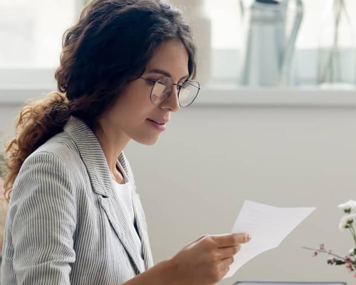 A woman looking at mail, potentially in a home or personal finance context.