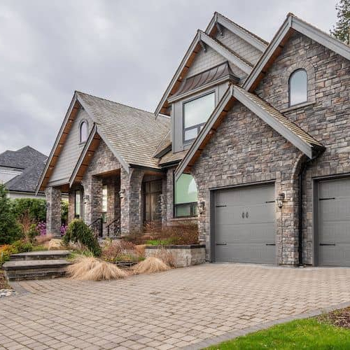 A large stone house with a stone driveway, showcasing a grand residential property.