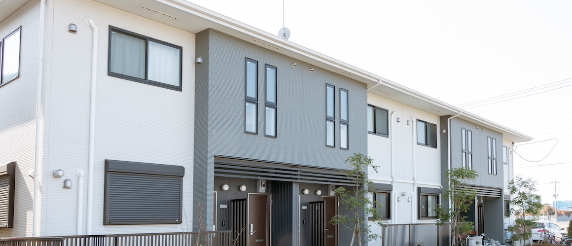 Closeup of a grey and white fourplex apartment.