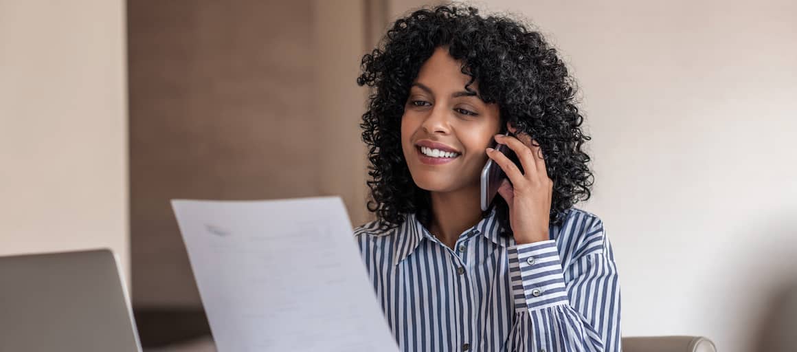 Woman on phone looking over financial documents.