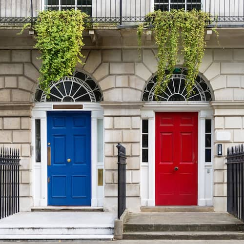 Front view of similar brick houses with red and blue door.
