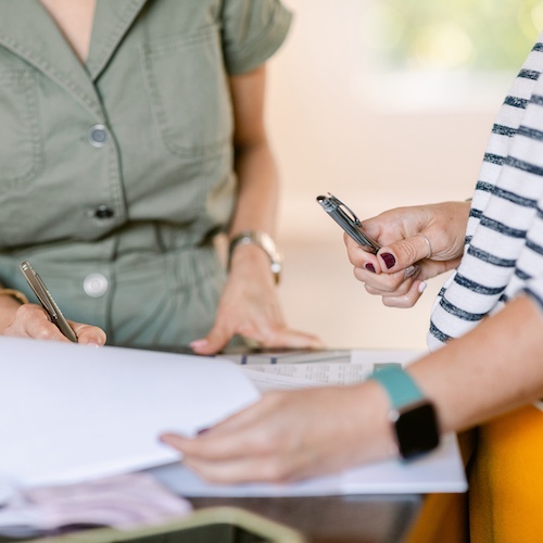 Realtor and client reviewing paperwork while standing up at a table.