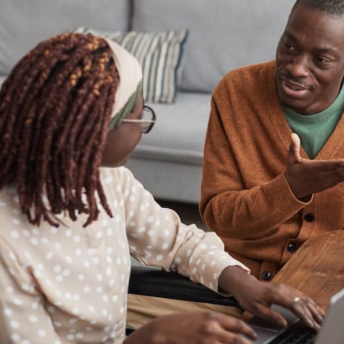 Young couple sitting at a table with a laptop and papers.