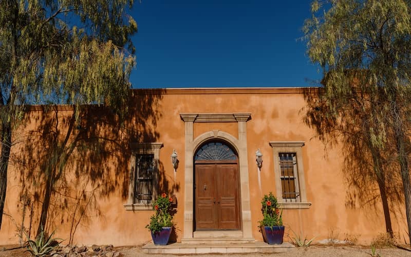 Mission Revival style home with an arched doorway and detailed trim around both the door and the windows. 