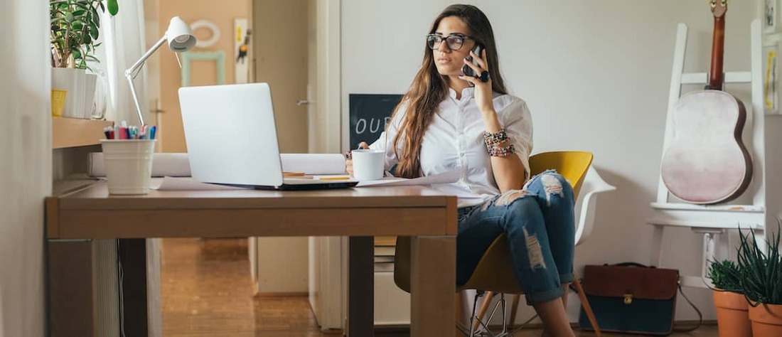  Woman on phone while checking computer, looking worried.