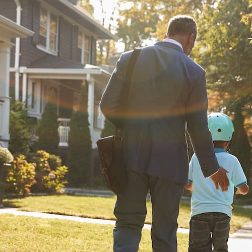 A dad walking with his son on a sidewalk.