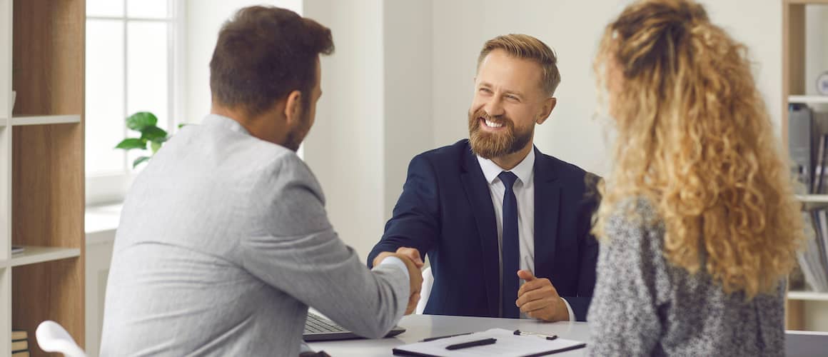 A financial advisor shaking hands with clients, possibly illustrating a successful financial consultation or agreement.