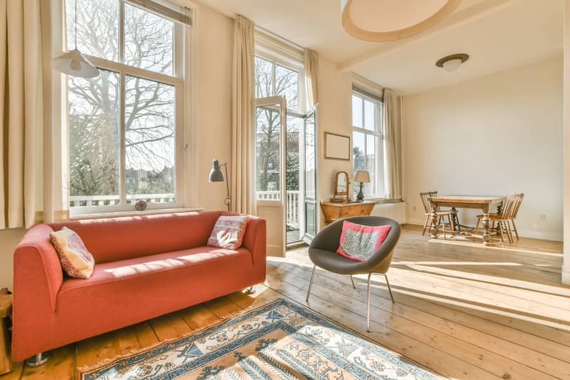 Sunny living room with limited furniture and wooden floors.