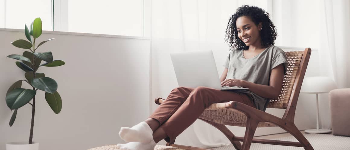 A woman using a laptop at home, likely managing finances or exploring real estate options online.