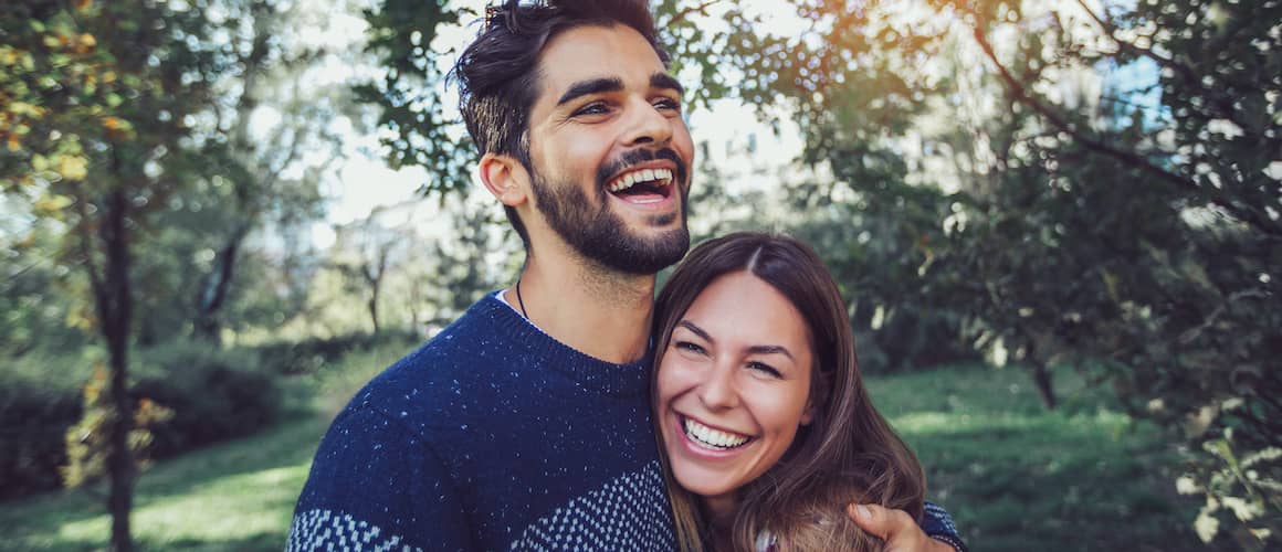 A couple smiling happily while enjoying a pleasant day in the park.