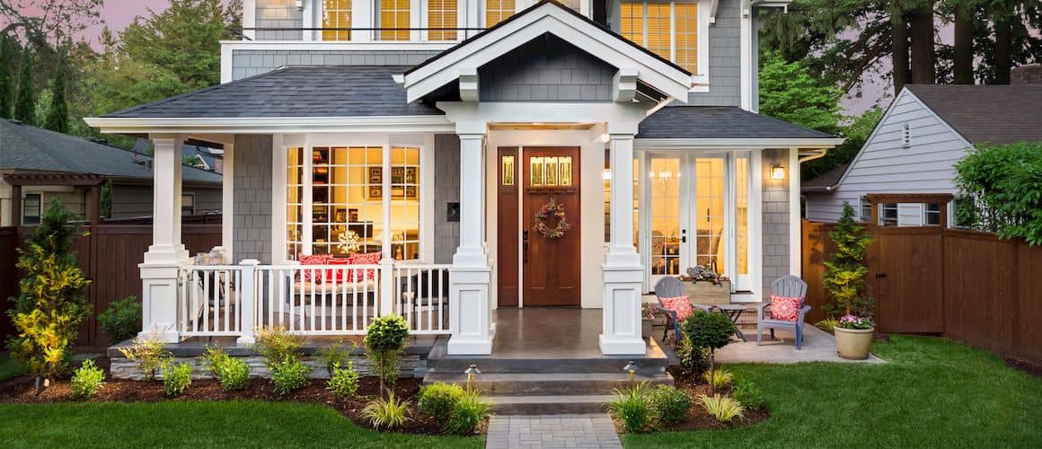 House with brick path and wrap-around porch in the evening.