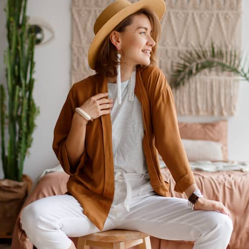 A fashionable women sitting on a stool looking outside, possible posing for a photo.
