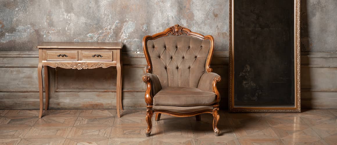 RHB Assets From IGX: An antique chair, mirror, and table set against a neutral-colored wall.