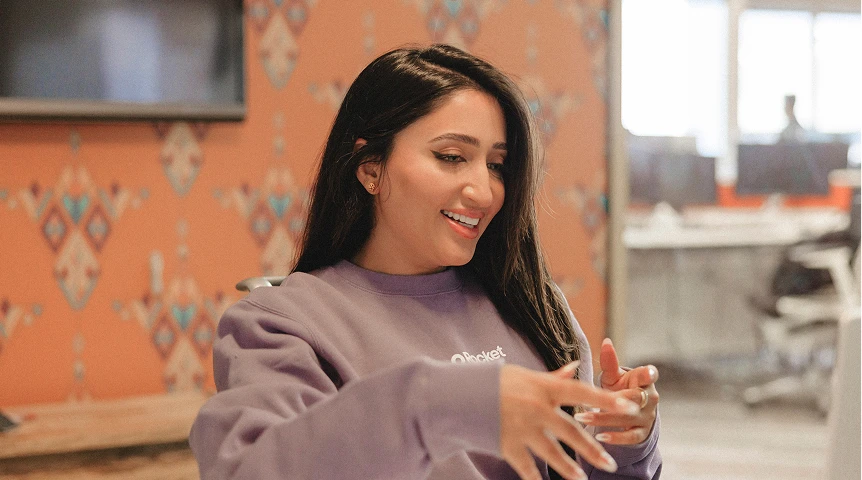 A person is seated, possibly clapping or holding something in their hands.