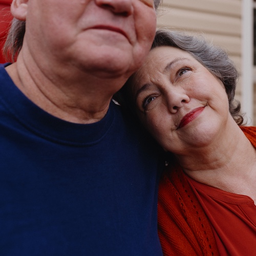 Woman with red lipstick looking up at man smiling.