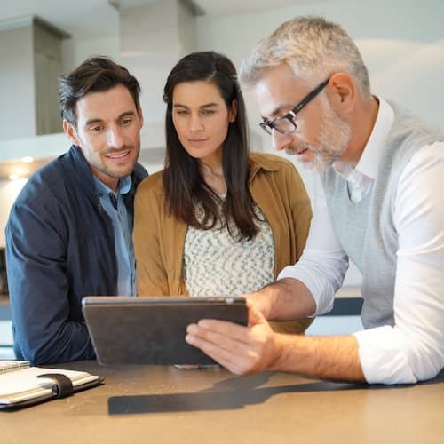 Three individuals discussing options listed on a tablet.