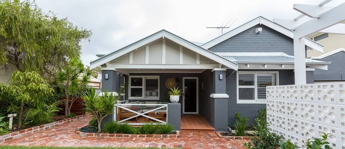 Small blue house in a backyard, showcasing a compact standalone house in a residential setting.