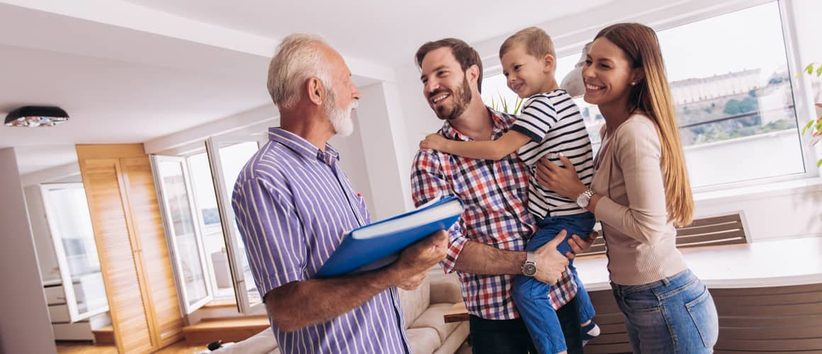 A family in a living room, with an old man holding a clipboard, possibly discussing or organizing something.