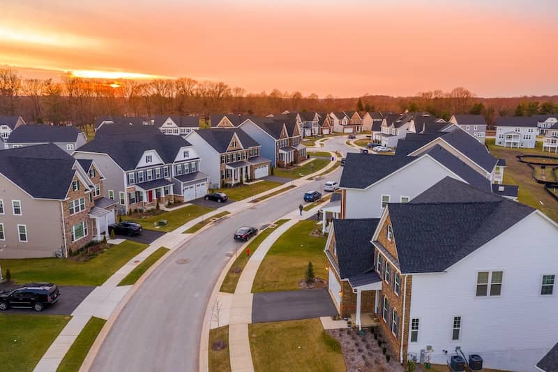 Neighborhood of mcmansion homes with sunset in background.