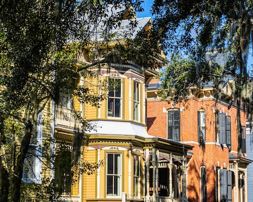 Old homes in Savannah, Georgia, seen through branches covered in Spanish moss.