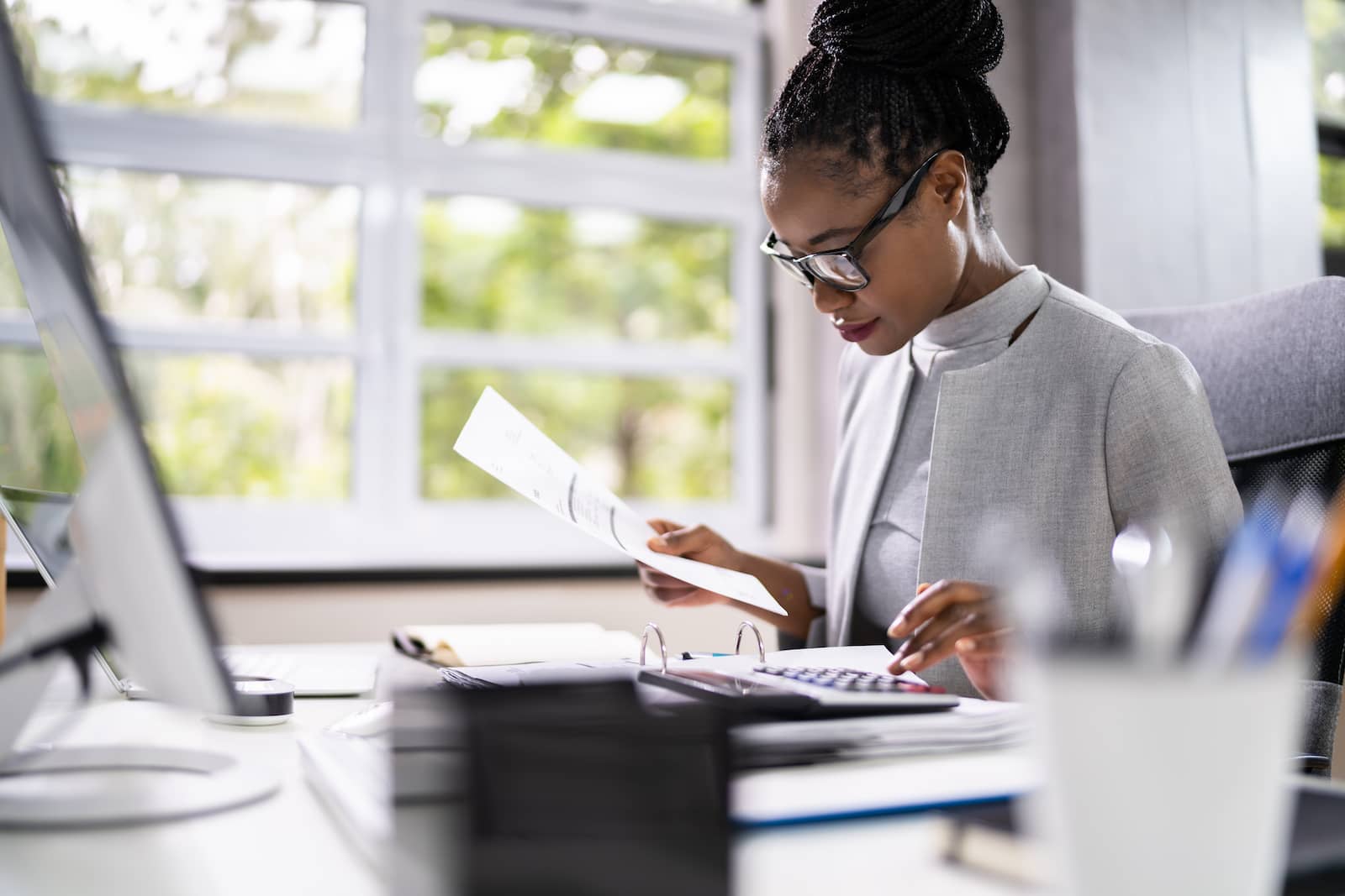 Woman doing taxes on desk with natural sunlight and papers 