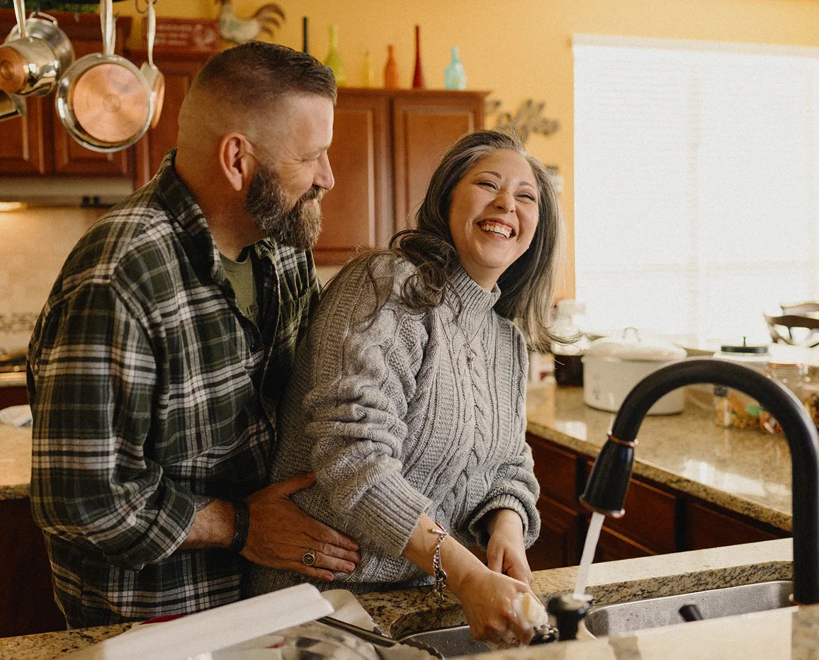Couple standing together in a kitchen.