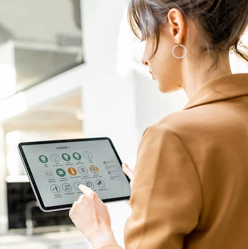 A woman viewing a smart home hub device, suggesting the concept of smart home technology and control.