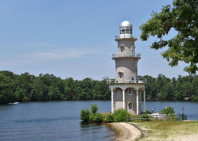 Grey and white lighthouse on water.