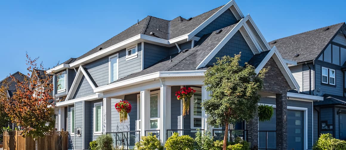 Large blue modern home with hanging flowers on porches.