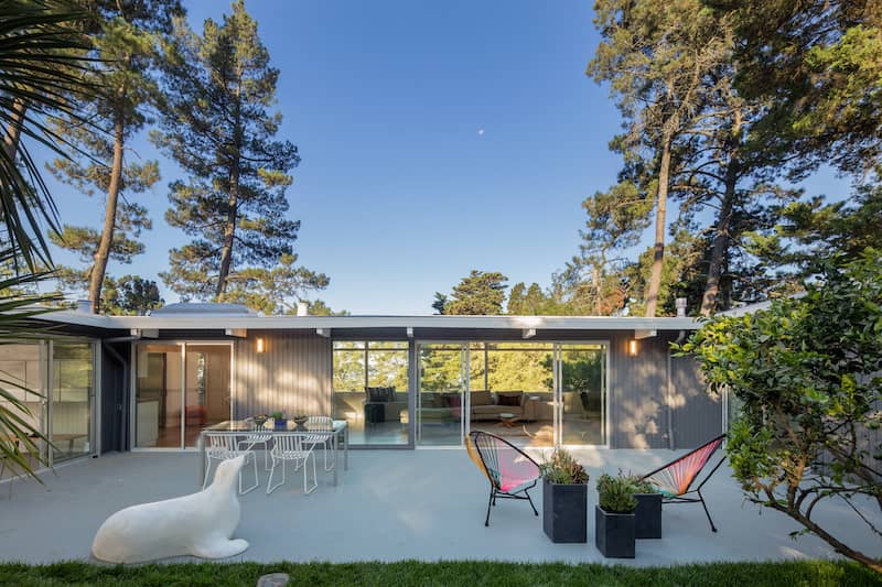 Exterior view of a midcentury modern home with modern outdoor furniture.