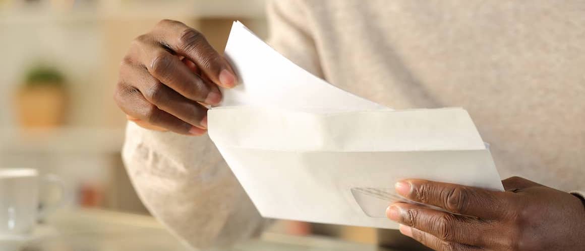 Man puts paper in envelope.