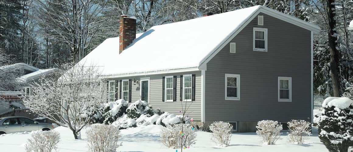 Single story house in winter with snow covering the rook.