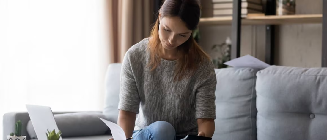 Woman in sweater sitting on a gray couch.