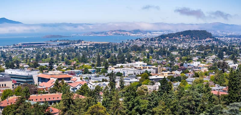 RHB Assets From IGX: Aerial view of Berkeley, California, with greenery, residential areas, and a bay in the background.