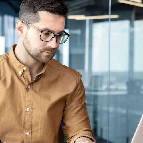 An analyst working in an office setting, focused on a laptop.