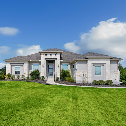 Suburban white house with large green front lawn.