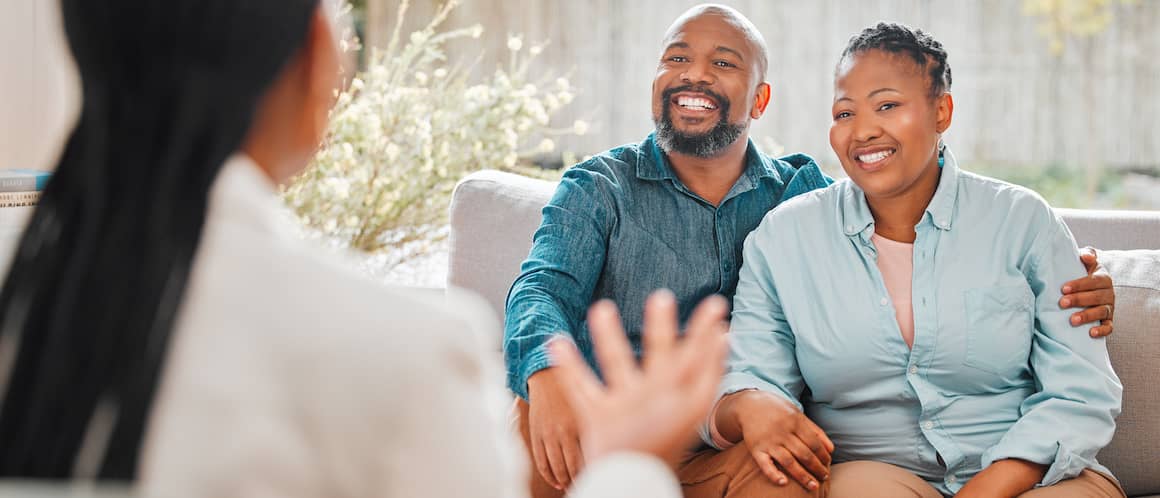 Middle-aged couple smiling while speaking with insurance agent.