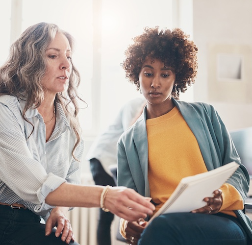 Women in office setting looking at documents together.