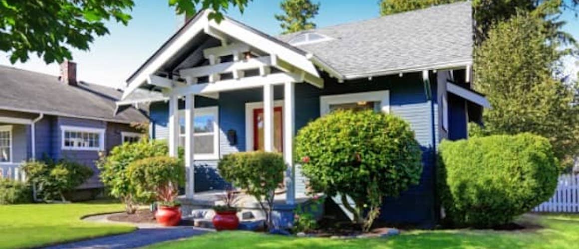 A cozy blue home with bright green grass.