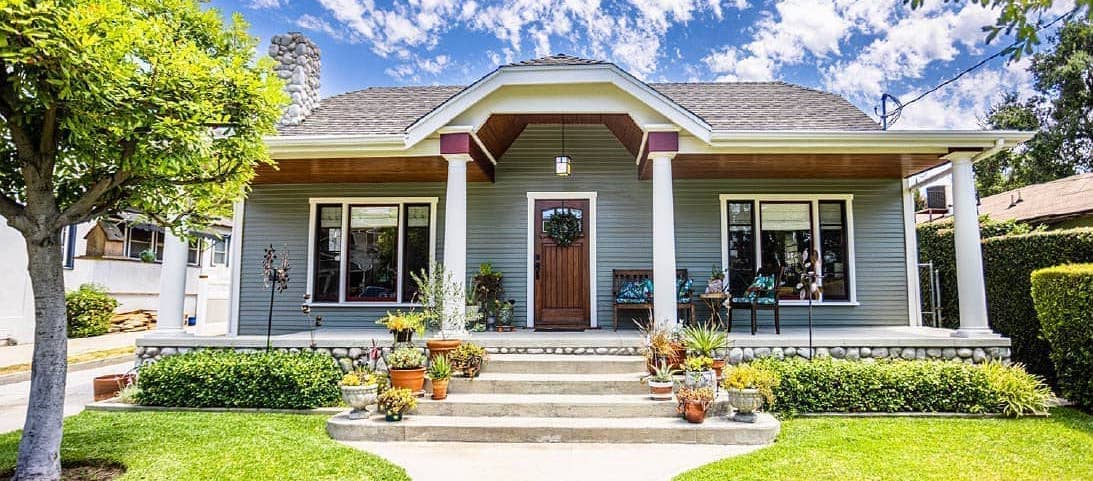 A cozy house with a charming porch and a well-maintained lawn.