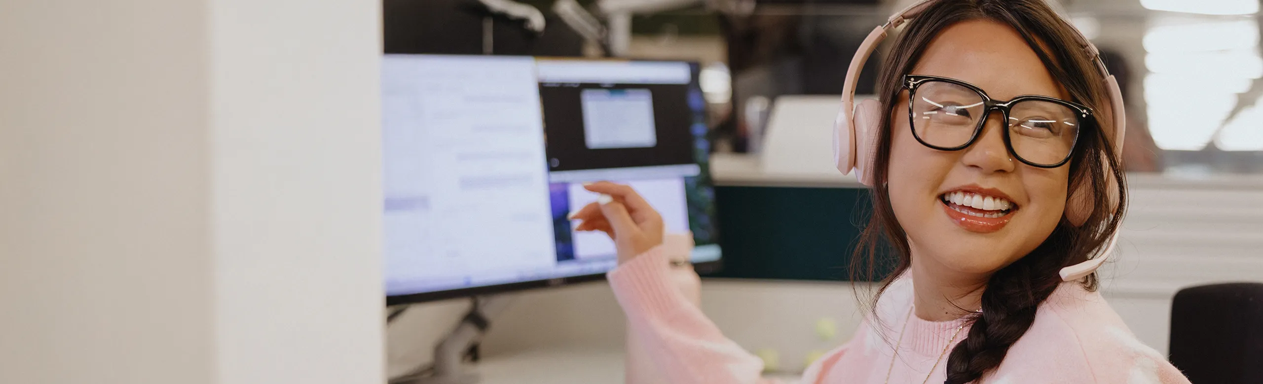Customer support representative wearing a headset and smiling at her desk in an office