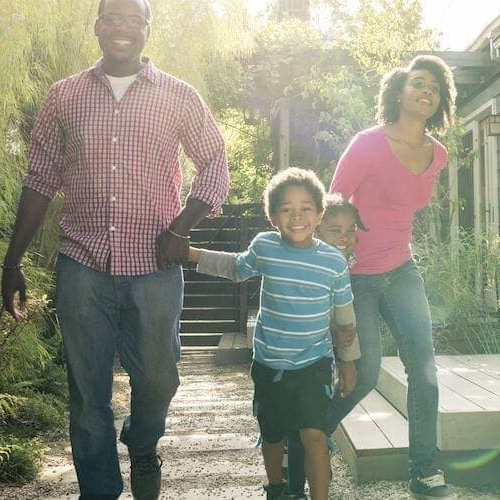 A family walking by a house, suggesting a family near or approaching a residential property.
